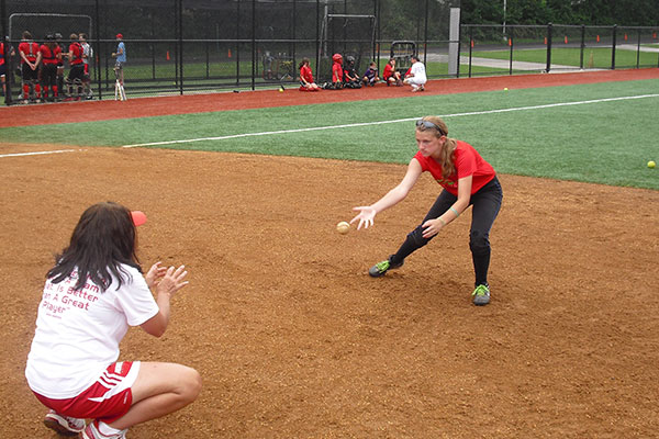 A pitcher and catcher do a softball drill together while at softball camp.